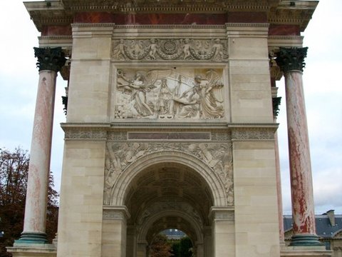 The pale stone arch with rose-marble columns and carved reliefs, a few visitors passing through its central opening.