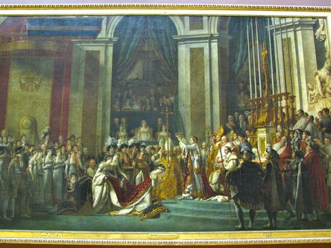 A vast gilt-framed canvas of a crowded coronation ceremony, robed figures gathered beneath columns and a raised golden cross.